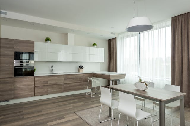 a modern kitchen and dining room with two-tone light wood and white cabinets